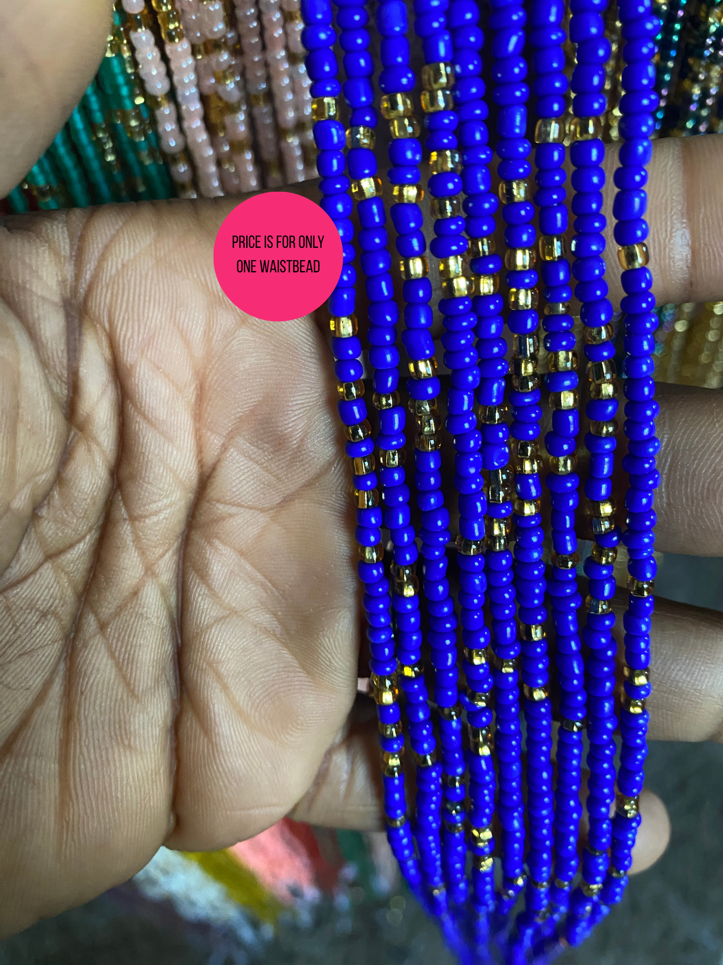 Close-up of blue beaded necklace with gold accents held between fingers.