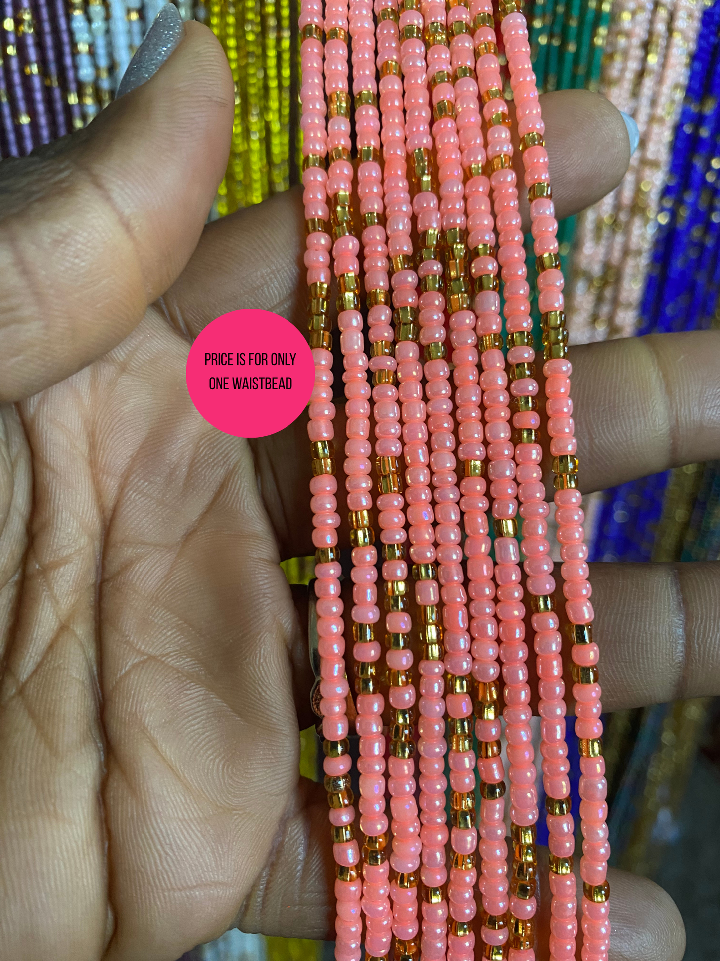 Pink beaded waist beads held by a hand with a pink label indicating price.