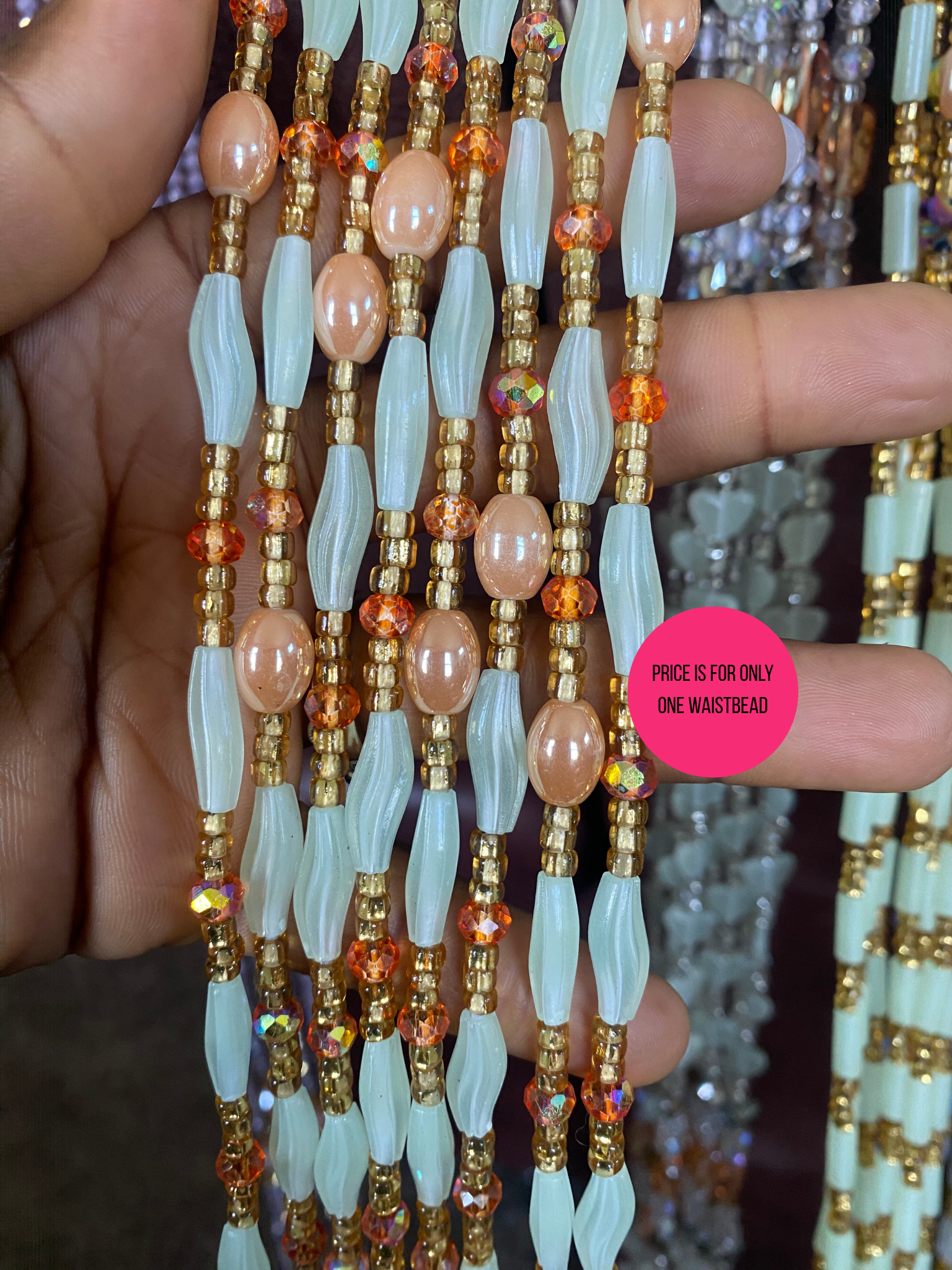 Close-up of a beaded waist bead with a pink label indicating price and quantity.