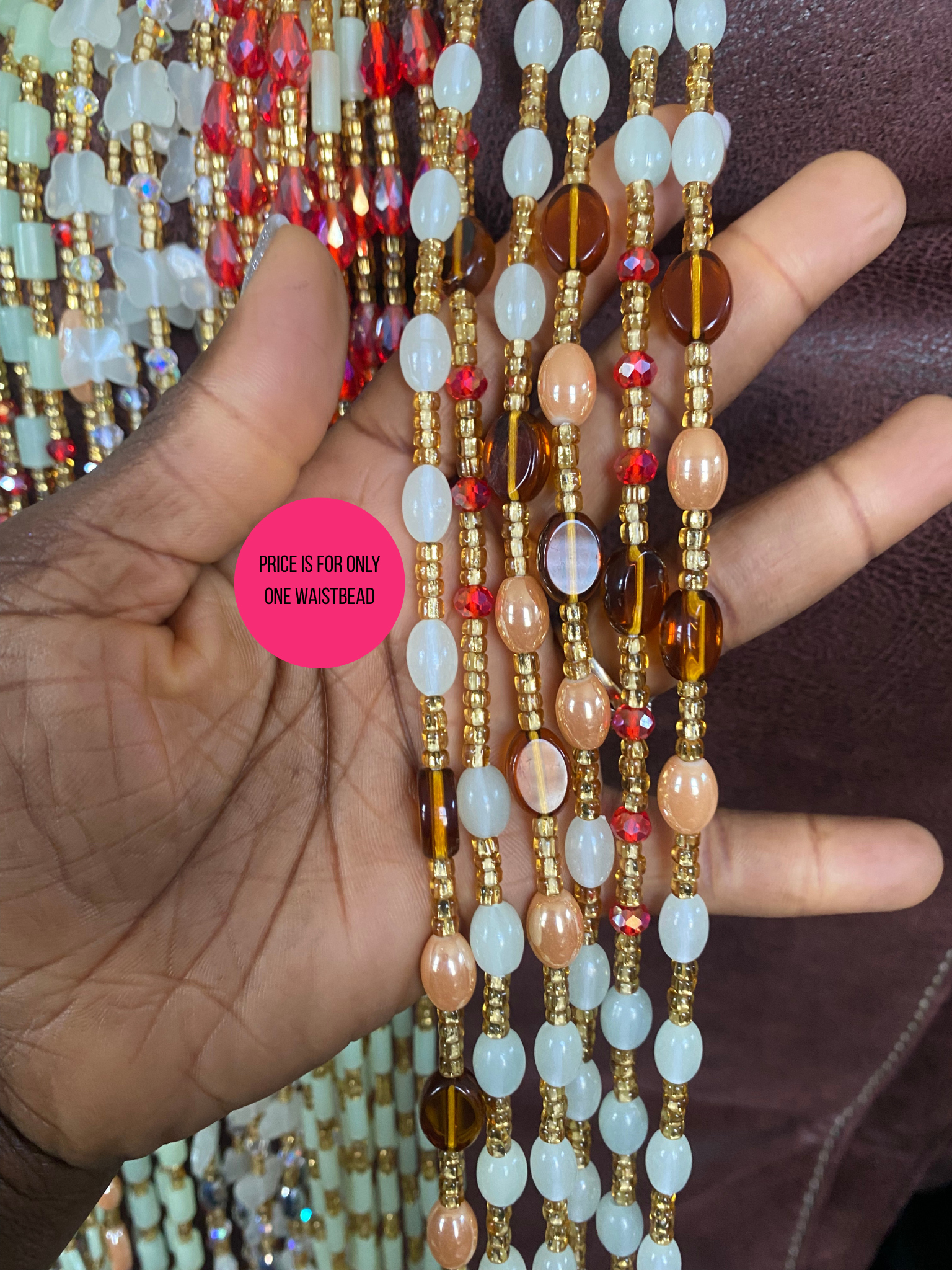 Hand holding a set of colorful Beaded Subtle Glow in the dark waist beads with a blurred background