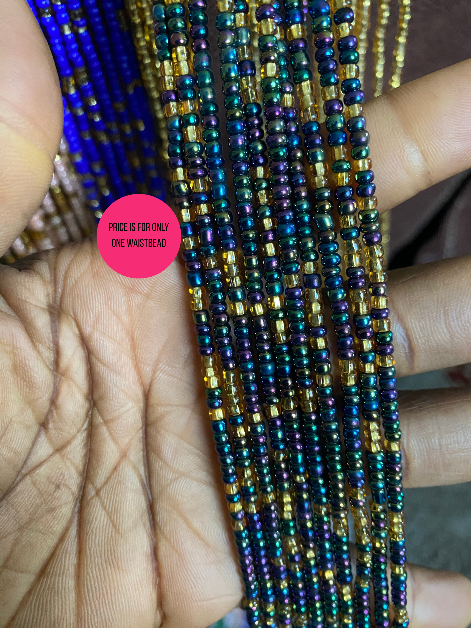 Close-up of multicolored beaded waist beads strands held between fingers with a pink label.