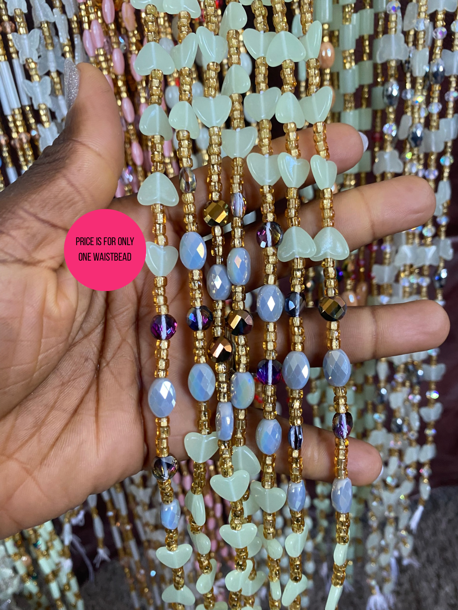 Close-up of a beaded waistbeads held by a hand with a pink price tag label.